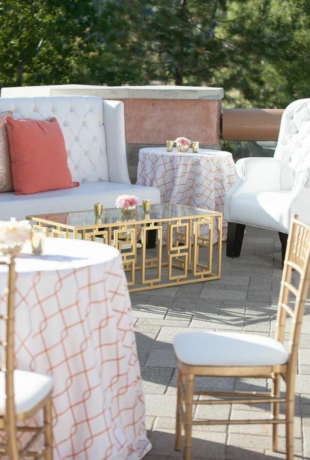 Luxury event furniture cost example with white tufted lounge seating, gold coffee table, cocktail tables, and outdoor décor.
